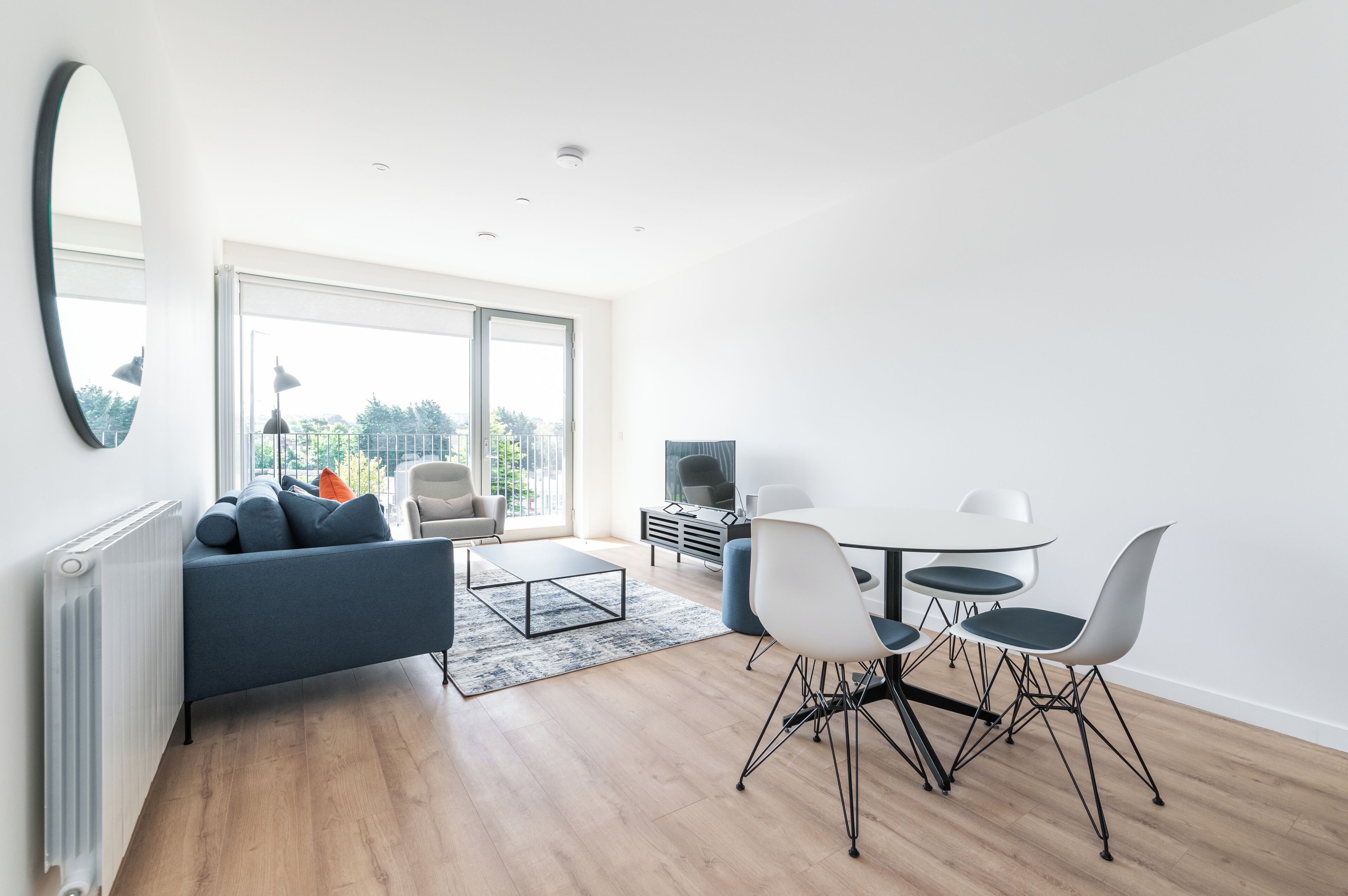 Ein modernes Wohnzimmer mit Sofa, Couchtisch und Esstisch mit Stühlen.