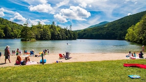A lakeside beach with people relaxing and engaging in water activities. - Private 5-BR Mountain Estate 10-Min to Manchester (Dorset)