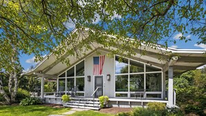 A modern house with a covered porch, a flag, and a well-maintained garden. - Private 5-BR Mountain Estate 10-Min to Manchester (Dorset)