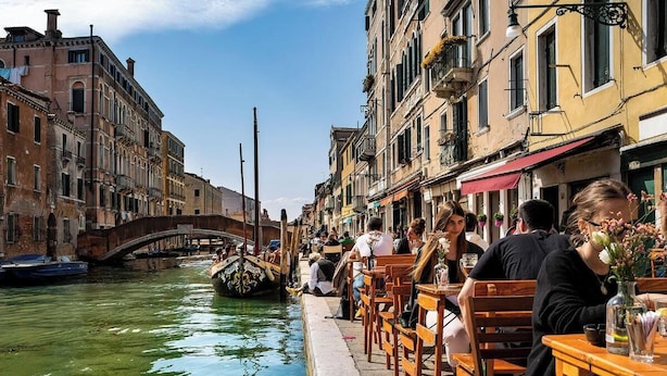 A canal-side restaurant with outdoor seating, a bridge, and historic buildings. - Charming and Elegant Venetian Retreat with Rooftop Views
 (Venezia)