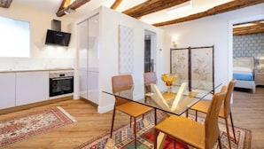 A modern kitchen with white cabinets, a built-in oven, and a flat-screen TV. - Charming and Elegant Venetian Retreat with Rooftop Views
 (Venezia)