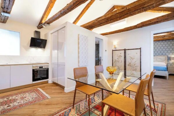 A modern kitchen with white cabinets, a built-in oven, and a flat-screen TV.