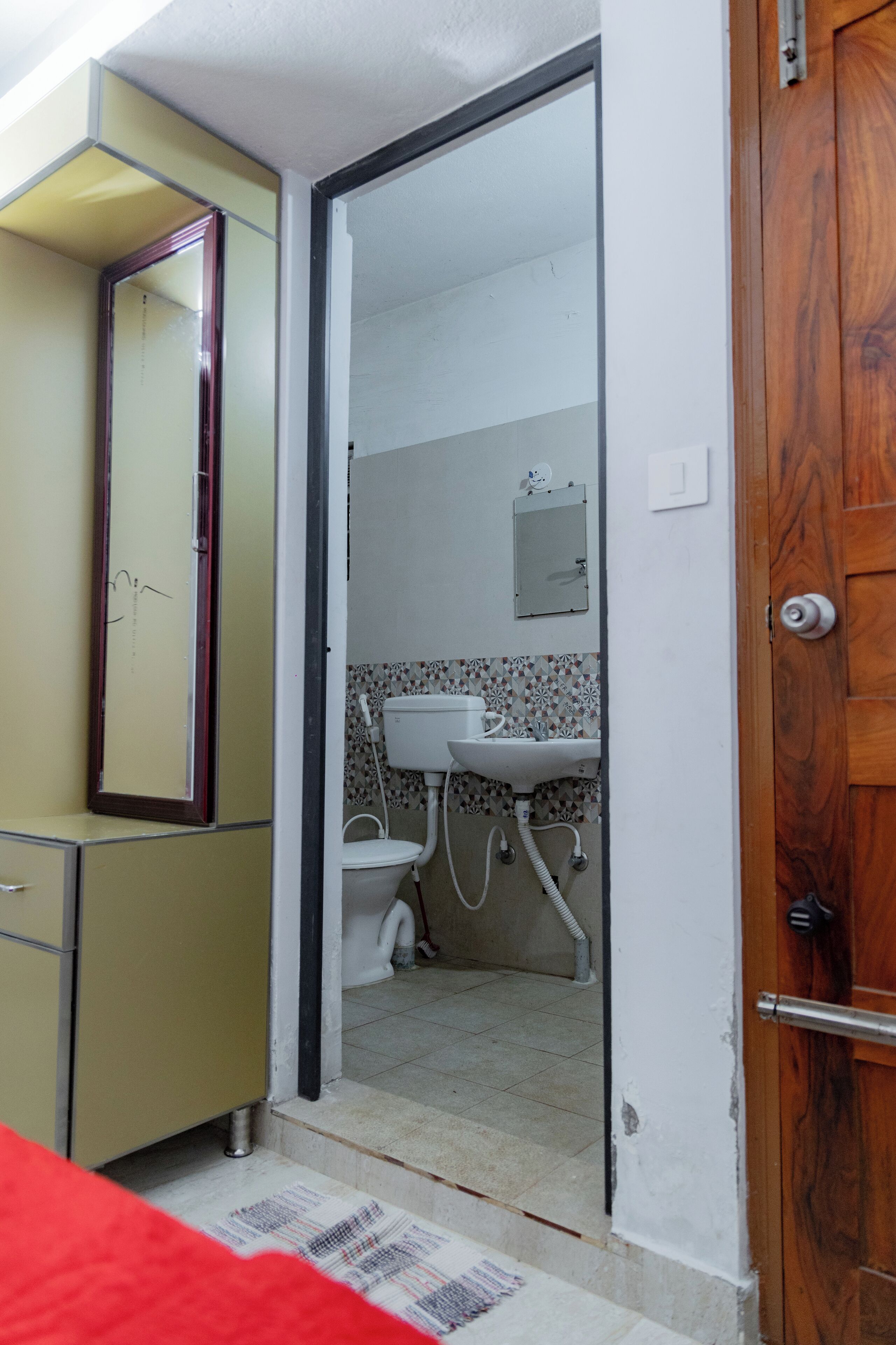 A narrow doorway leading to a bathroom with a toilet, sink, and mirror.
