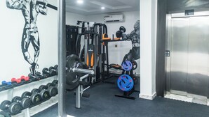 A gym with weightlifting equipment, a wall-mounted air conditioner, and a door to a hallway. - Luxury Hotel Deluxe Room - Sleeps 2 - Gym - Pool (Lekki)