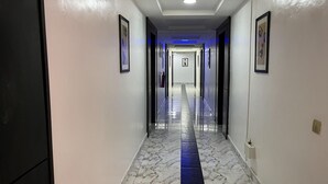 A hallway with a marble floor, framed pictures on the walls, and a blue-lit ceiling. - Luxury Hotel Deluxe Room - Sleeps 2 - Gym - Pool (Lekki)