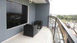 Ein Balkon mit Blick auf die Stadt, ein schwarzes Sofa und ein kleiner Tisch.