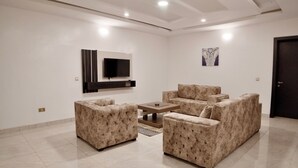 Ein modernes Wohnzimmer mit einem Flachbildfernseher an der Wand, einem Couchtisch und zwei Sofas.