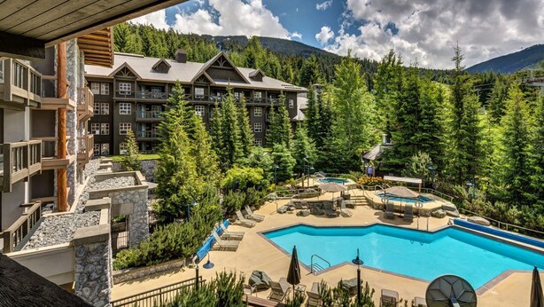 Ein Resort mit großem Pool, mehreren Gästezimmern und einer Bergkulisse.