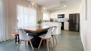 Une cuisine moderne avec un îlot central en bois, des meubles blancs et des appareils électroménagers en acier inoxydable.