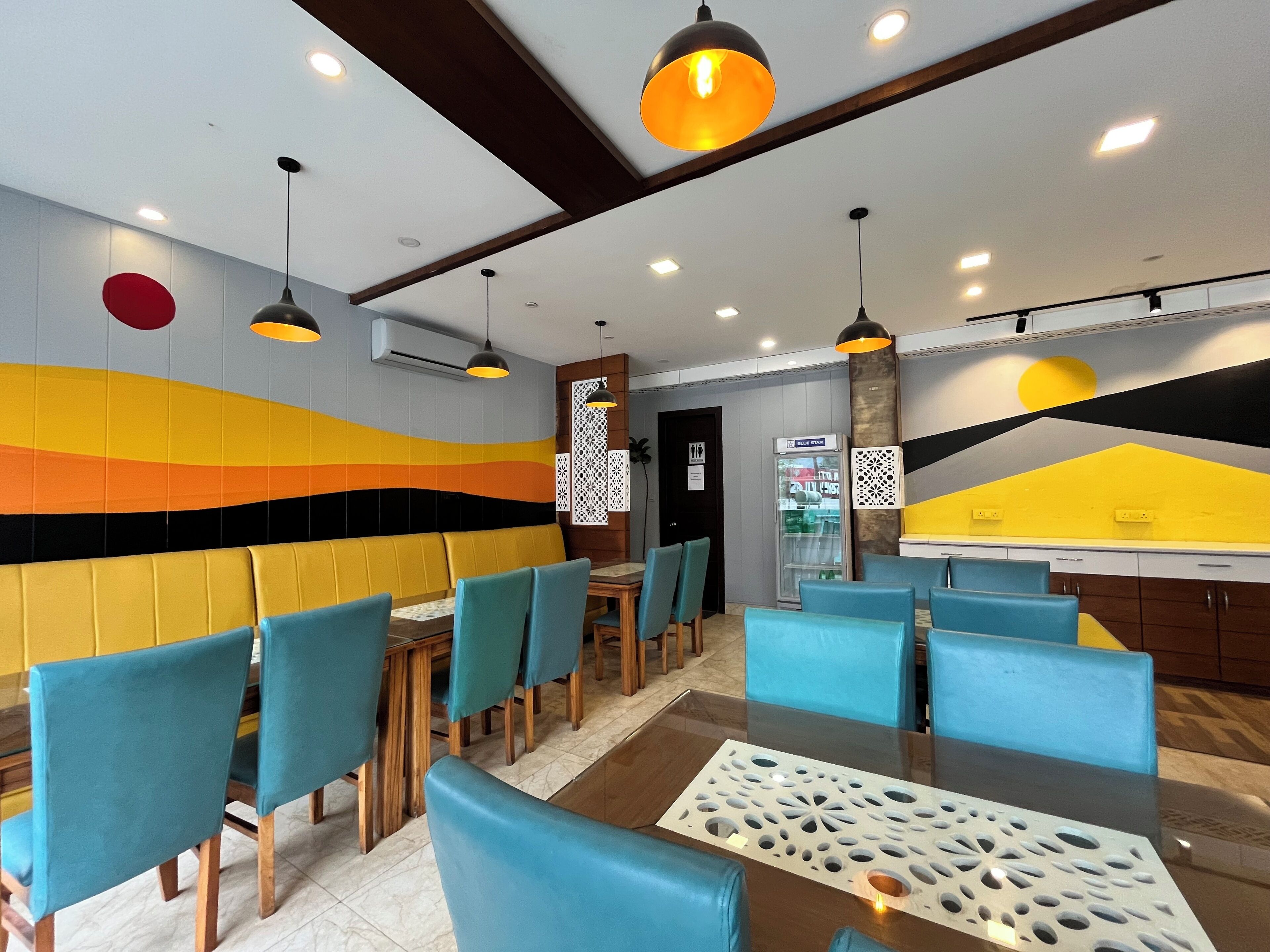 Un intérieur de restaurant moderne, avec un mur aux couleurs vives, des chaises bleues et des tables en bois.