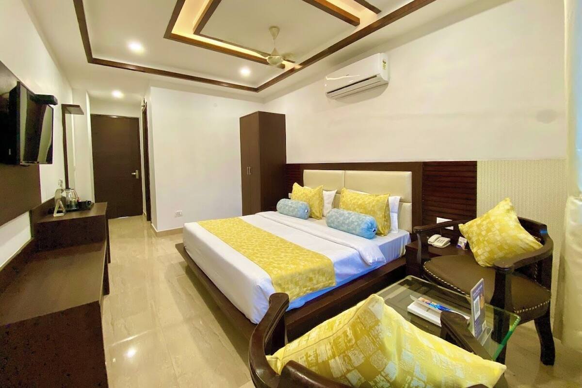 A hotel room with a bed, bedside table, chair, and a ceiling fan.