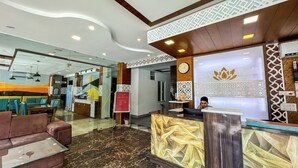 A hotel lobby with a reception desk, seating area, and a clock on the wall. - HOTEL SHIV VILAS (Rishikesh)