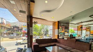 A modern interior with a glass coffee table, leather sofa, and a view of the street outside. - HOTEL SHIV VILAS (Rishikesh)