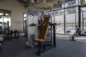 A gym with exercise equipment, large windows, and a view of the outside. - Executive Studio at Upside Living With Burj Views (Dubai)