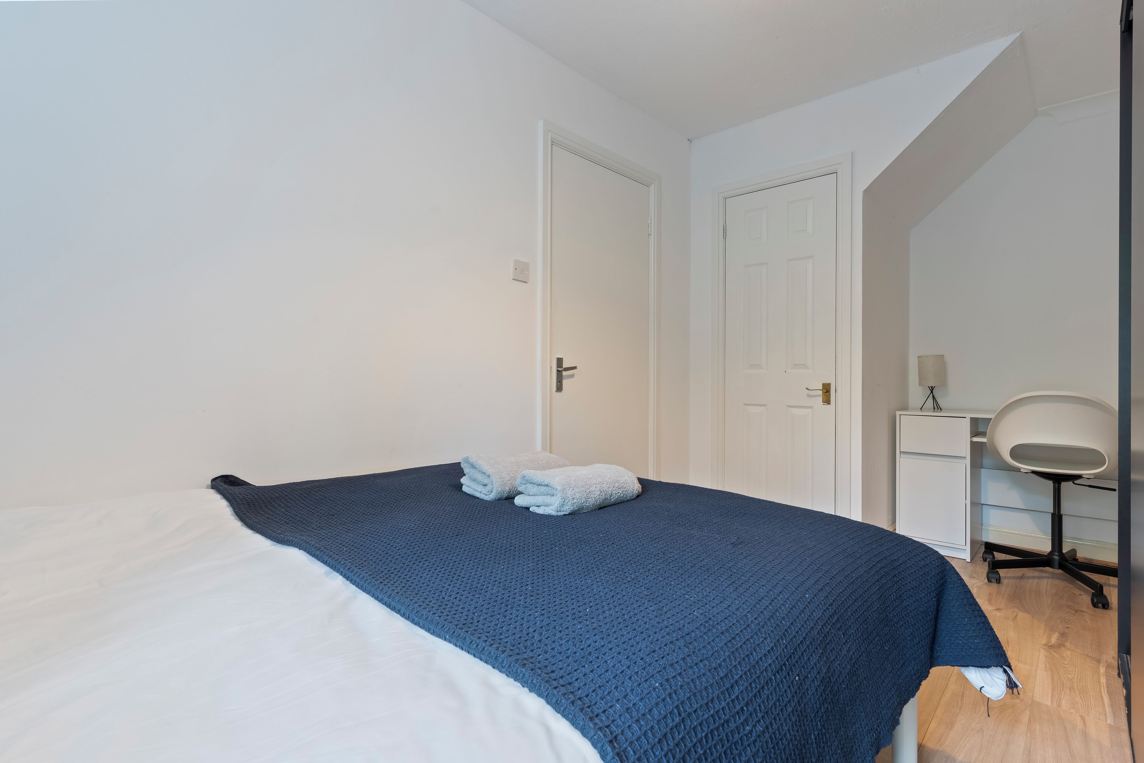 A bedroom with a bed, a desk, and a chair.