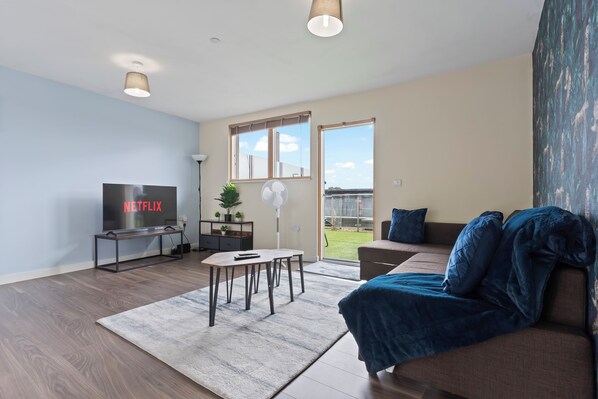 A modern living room with a flat-screen TV, a coffee table, a sofa, and a large window. - Retreat Private Rooftop 3 Bedroom Apartment (London)