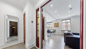 A spacious living area with a dining table and chairs, a sofa, and a large window providing natural light. - London Chic Apartment - City Center Gem (London)