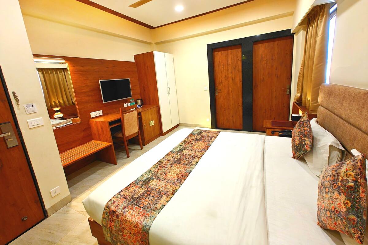A hotel room with a bed, a desk, a television, and a wardrobe.