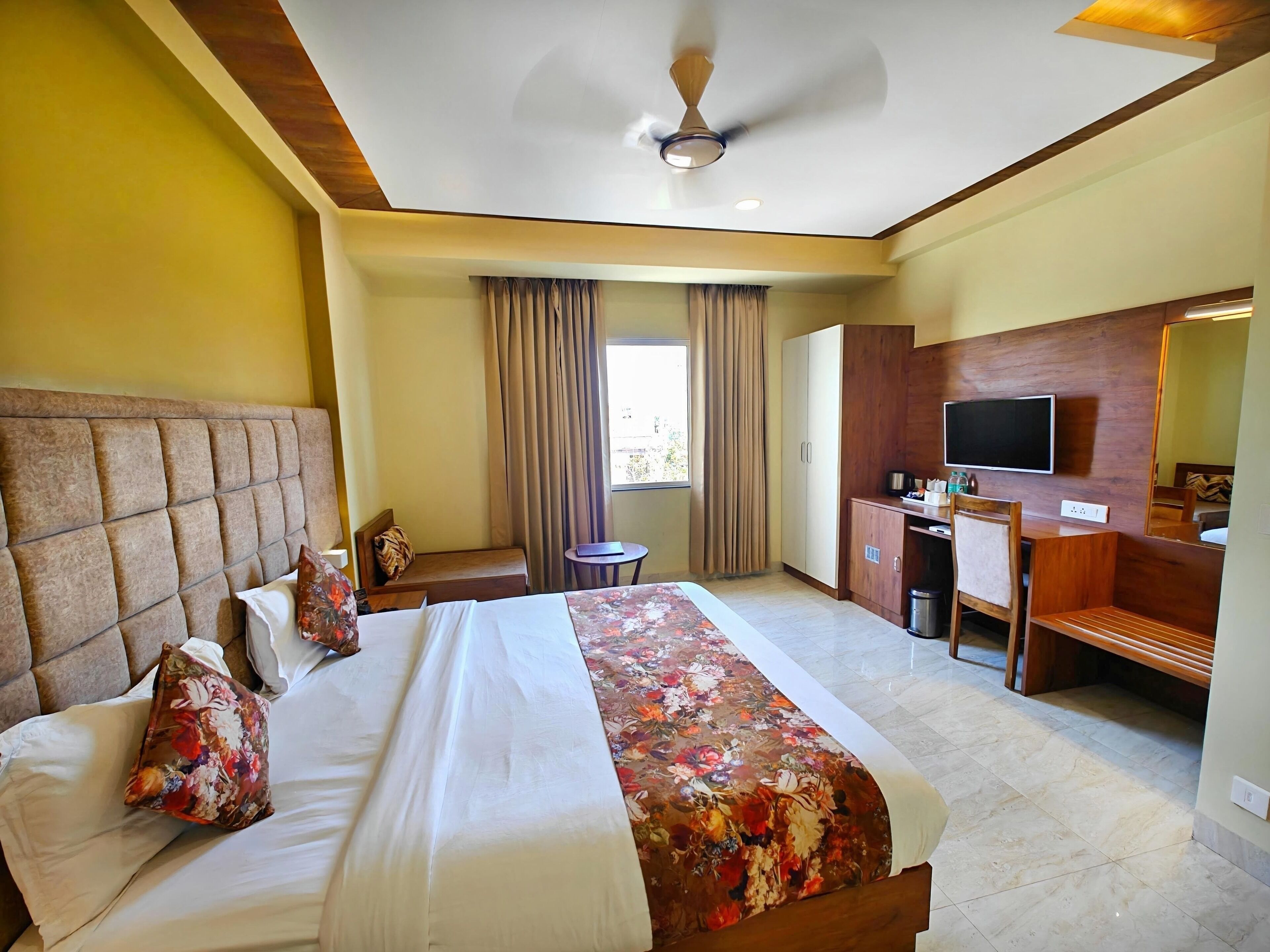 Une chambre d’hôtel avec un grand lit, un bureau, une télévision et un miroir.