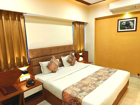 A hotel room with a bed, nightstands, a telephone, a power outlet, and a framed picture on the wall. - Hotel Opulence Inn (Udaipur)