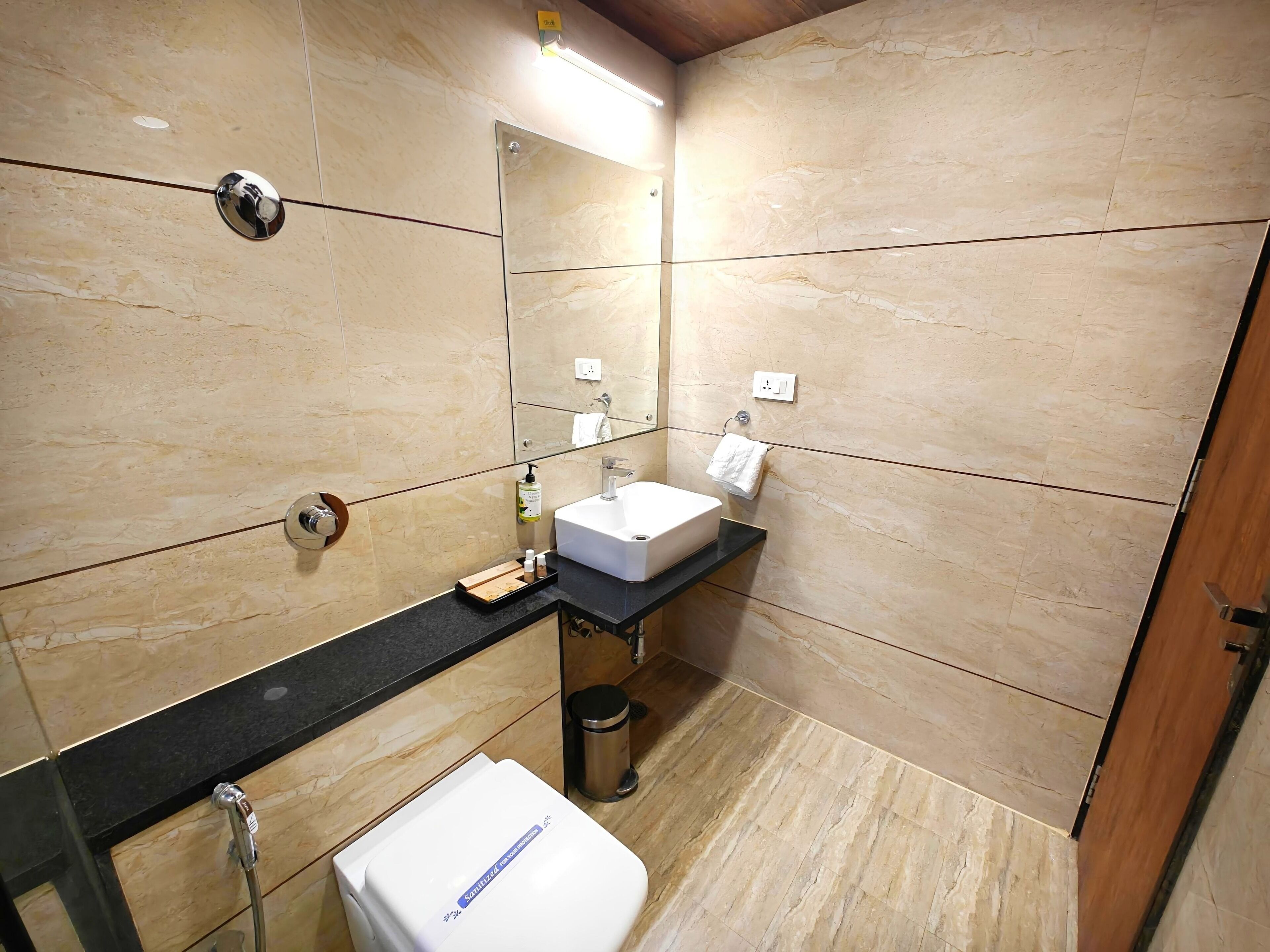 A modern bathroom with a marble floor, a white sink, a mirror, and a shower.
