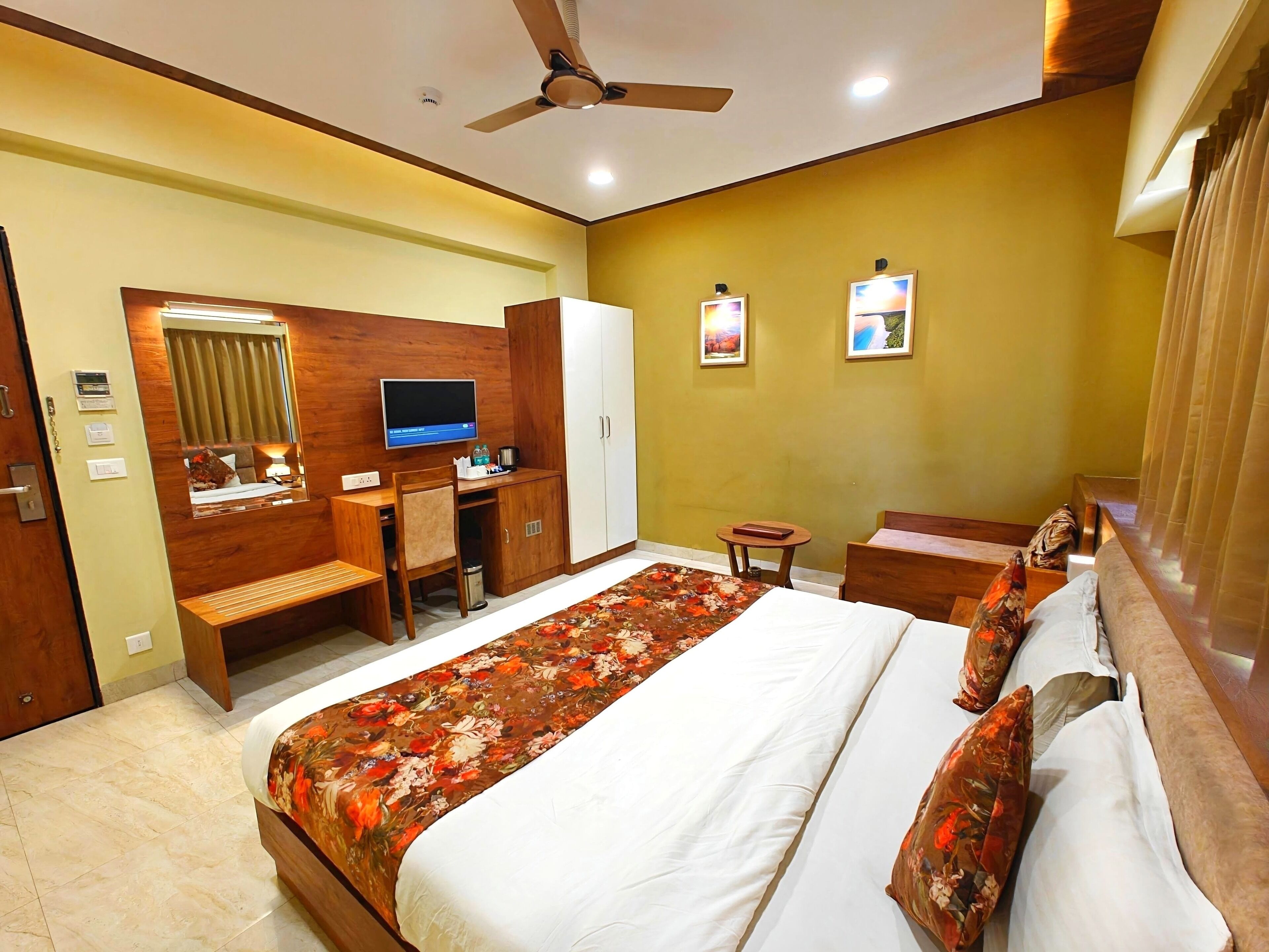 Ein Hotelzimmer mit Bett, Schreibtisch, Stuhl und Deckenventilator.