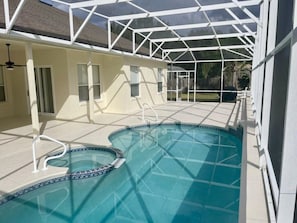 A swimming pool with a glass enclosure, a covered patio area, and a view of a backyard. - Hampton Lakes Villa (Davenport)