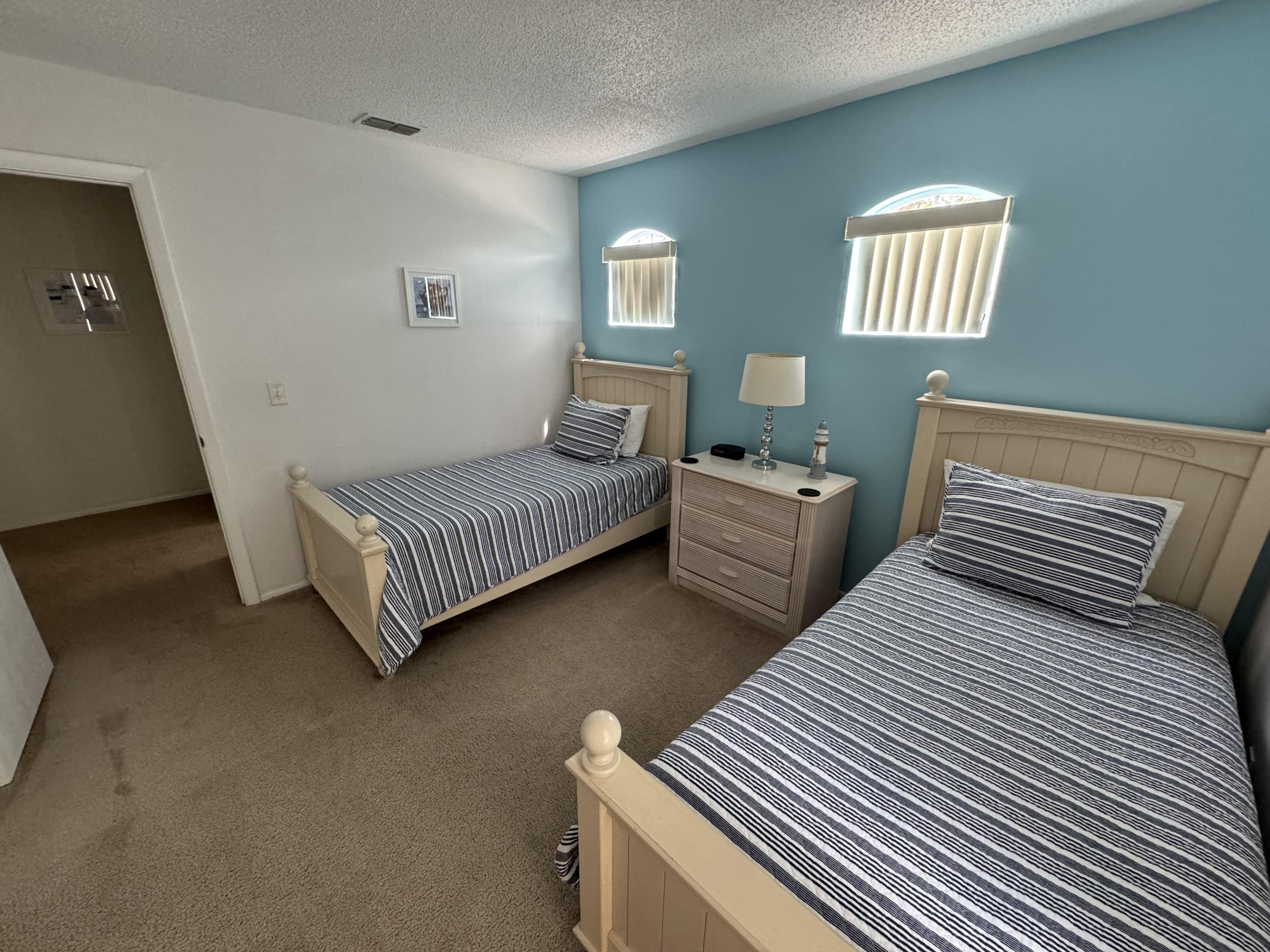 Un dormitorio con dos camas, una mesita de noche, un aparador y una puerta.