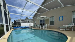 An indoor swimming pool with a covered patio area, lounge chairs, and a pool table. - Julliard Villa (Davenport)
