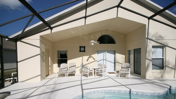 A covered outdoor pool area with lounge chairs and a ceiling fan. - Cumbrian Retreat (Kissimmee)