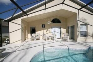 Un área de piscina techada con sillones de descanso y un ventilador de techo.