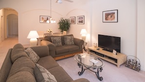 A living room with a sofa, a coffee table, a TV, and a lamp. - Cumbrian Retreat (Kissimmee)
