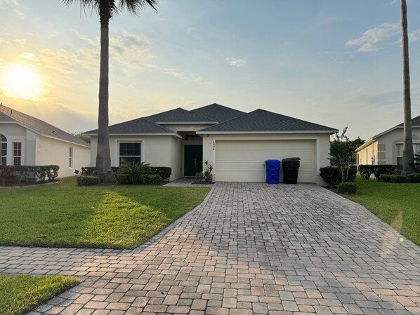 A residential house with a paved driveway, a garage, and a well-maintained lawn.