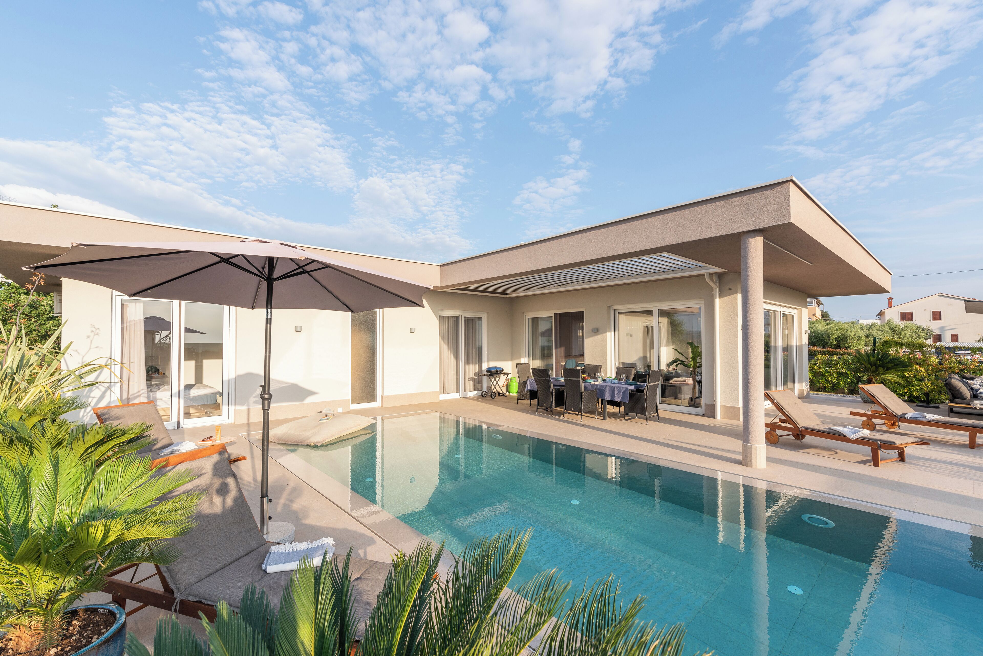 A modern house with a swimming pool, outdoor furniture, and a covered patio area.