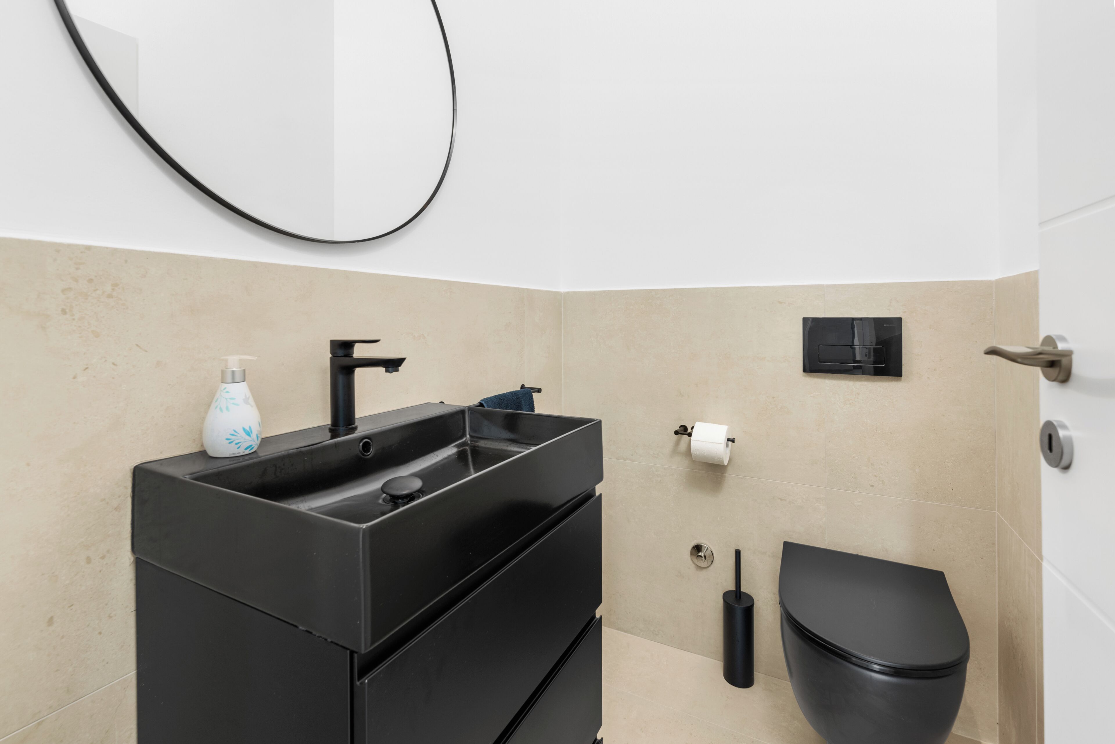 Ein modernes Badezimmer mit einem schwarzen Waschbecken, einer Toilette und einem Handtuchhalter.