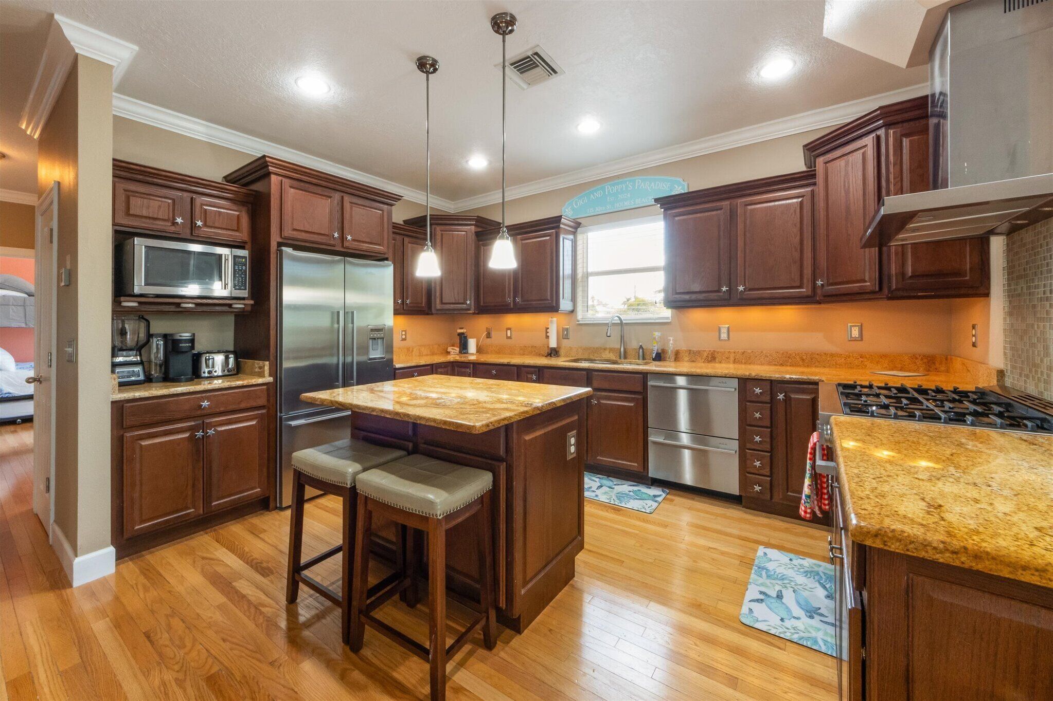 A modern kitchen with wooden cabinets, stainless steel appliances, and a granite countertop island.