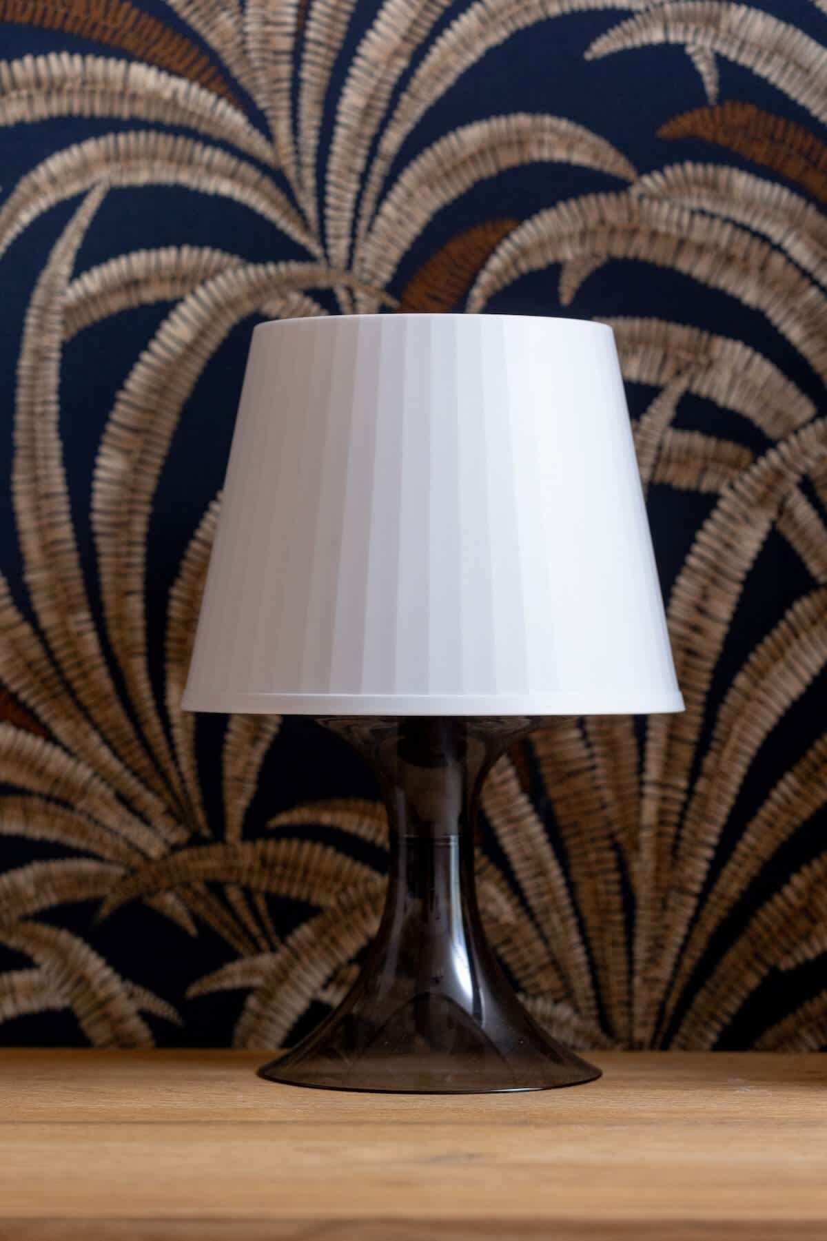 Una lámpara de mesa con pantalla acanalada sobre una superficie de madera.