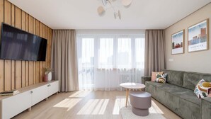 A modern living room with a flat-screen TV, a grey sofa, a round coffee table, and a wooden cabinet. - Stylish Apartment in the Center | Air Conditioning, Balcony (Katowice)