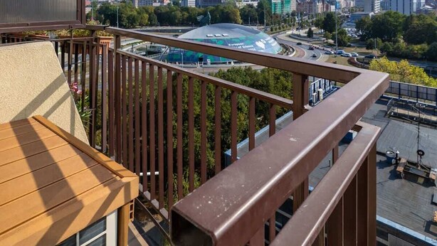 A balcony with a view of a cityscape, including a large stadium and modern buildings. - Stylish Apartment in the Center | Air Conditioning, Balcony (Katowice)