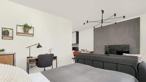 Ein modernes Schlafzimmer mit Bett, Schreibtisch, Stuhl und einer Pendelleuchte.