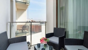 A balcony with wicker furniture, a glass table, and a vase of flowers. - Stylish Studio in the Center | Air Conditioning, Balcony (Poznan)