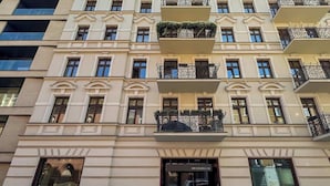 A multi-story building with a classic architectural style, featuring balconies with wrought iron railings and a ground-level entrance with a glass door. - Stylish Studio in the Center | Air Conditioning, Balcony (Poznan)
