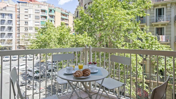Een balkon met een ontbijtje, met uitzicht op een drukke straat en gebouwen.