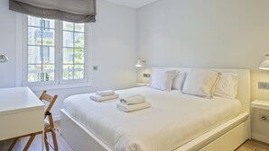 Een moderne slaapkamer met een groot bed, nachtkastjes, een bureau en een stoel.