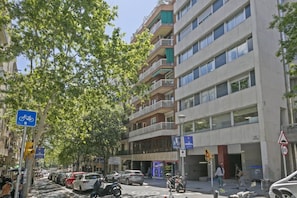 Um edifício com várias andares, varandas, placa de estacionamento para bicicletas e faixa de pedestres.