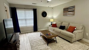 Una sala de estar con ventilador de techo, televisor, una mesa de centro, sofá y alfombra.