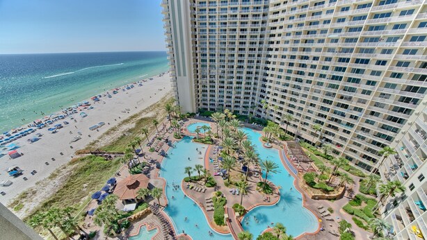 A high-rise hotel with a pool area, beach access, and a view of the ocean.
