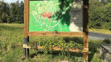 A wooden information board with a map and text in a natural setting.