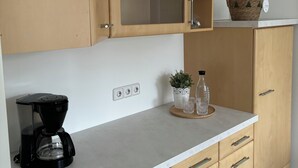 A kitchen with wooden cabinets, a coffee maker, a basket, and a potted plant on the countertop.