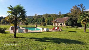 Une piscine entourée de chaises longues, avec une maison en arrière-plan.